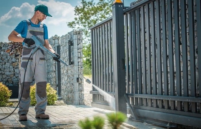 A man washing the front gate with a pressure washer