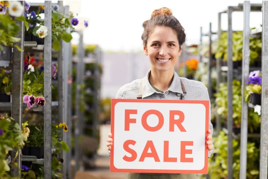 Woman holding business for sale sign