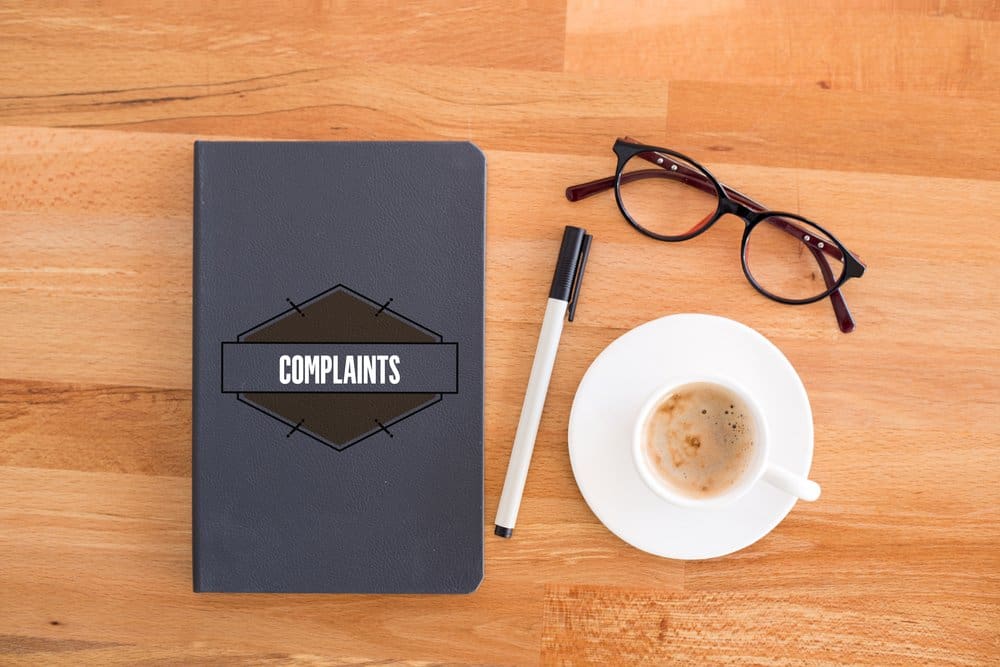 A black notebook and a cup of coffee on a desk