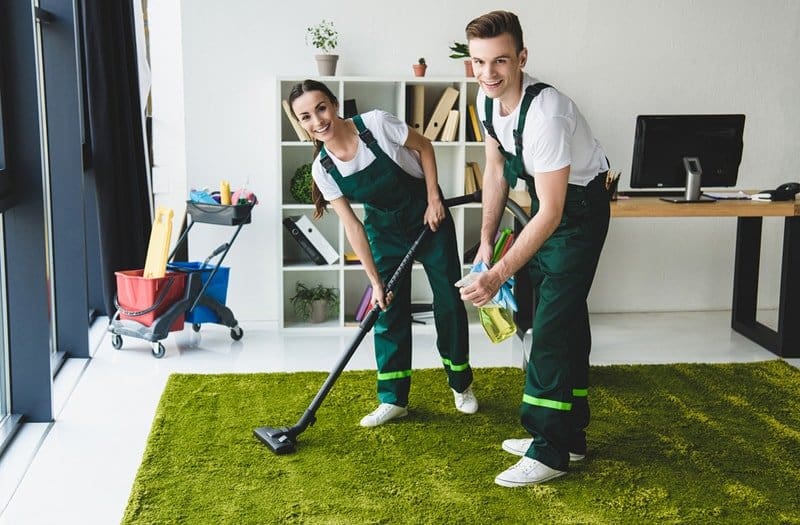 Happy cleaners cleaning a green carpet