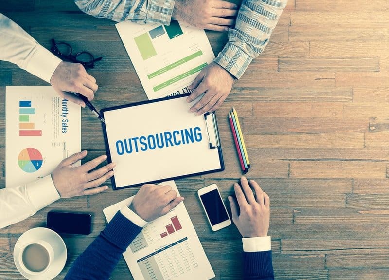 Group of people at a desk talking about outsourcing