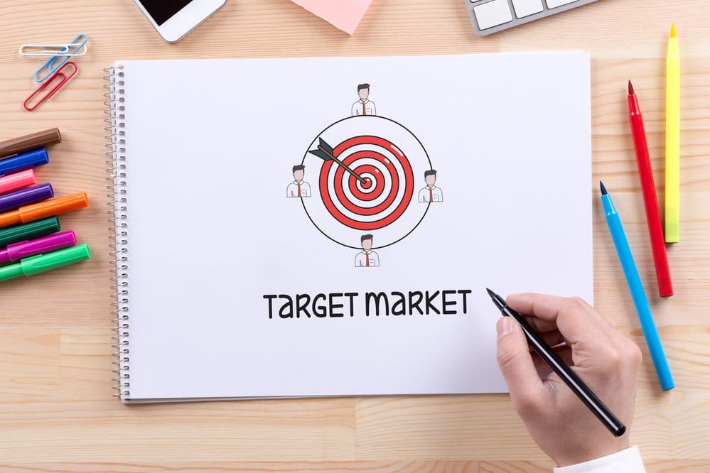 A man drawing a red dart board on a white sketch pad