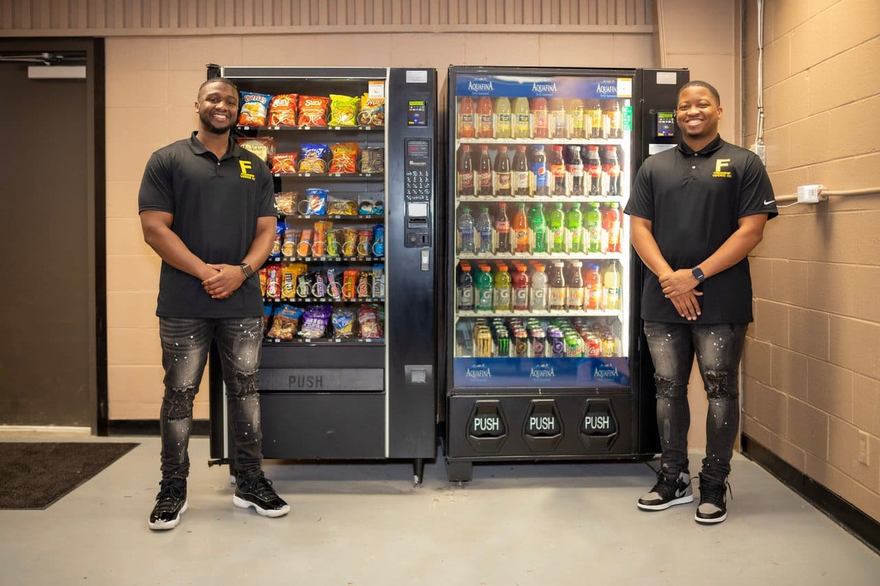Two-person standing at the sides of vending machine