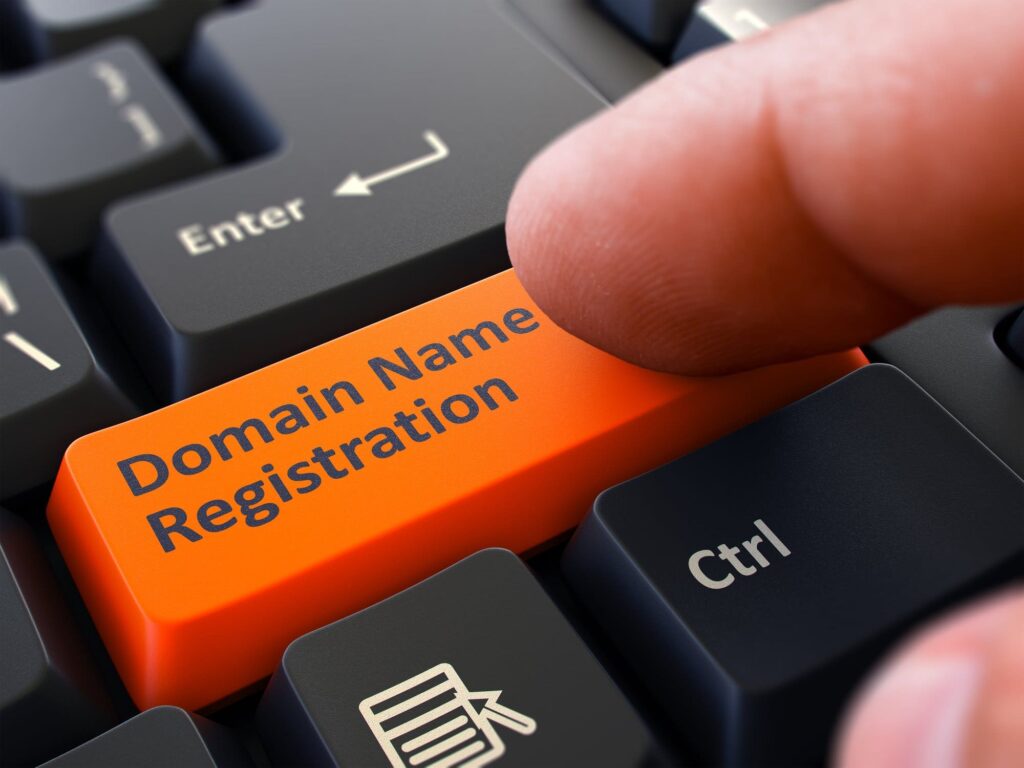Finger Presses Orange Button Domain Name Registration on black keys