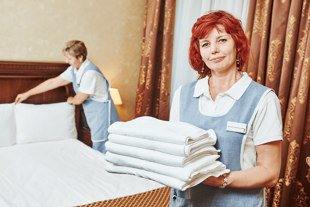Two female housekeeping staffs making bed in room
