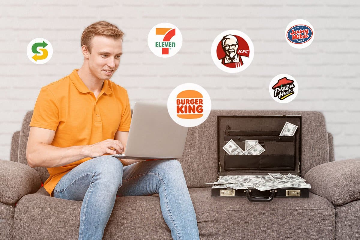 man sitting on sofa using laptop with briefcase full of money
