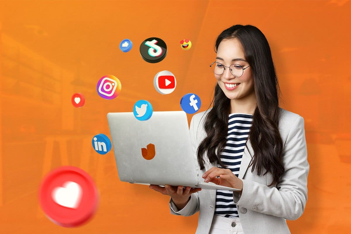 woman holding a laptop with social media icons floating around