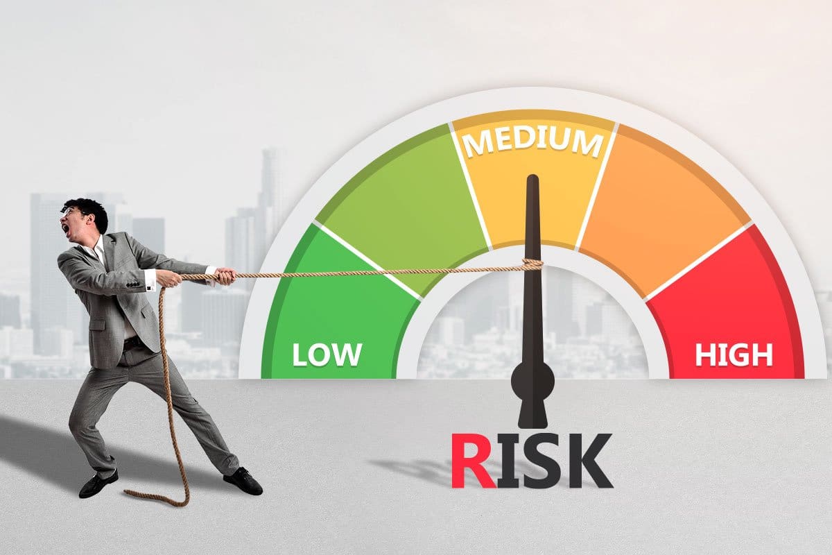 Concept of young businessman pulling a giant risk meter away from high and toward low