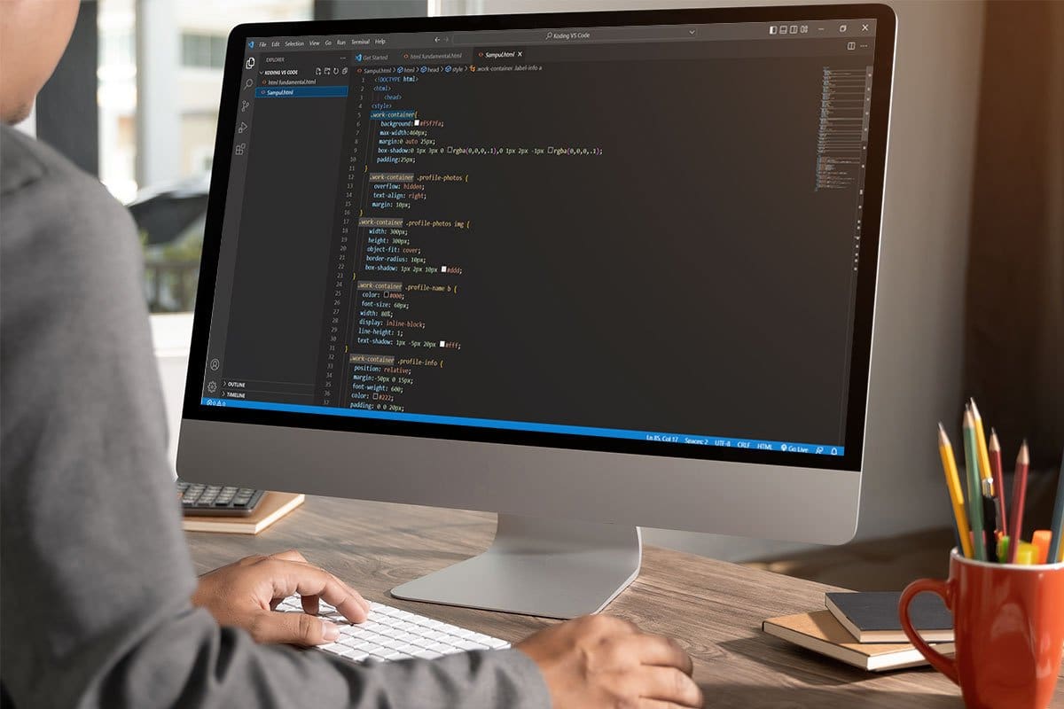 Software developer writing code on a large Mac monitor