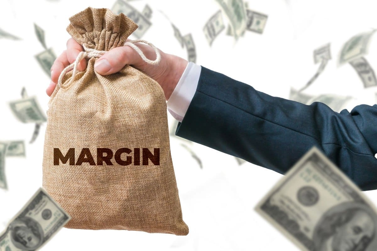 Hand holding a money bag with word "margin" printed on it, cash flying around in the foreground and background