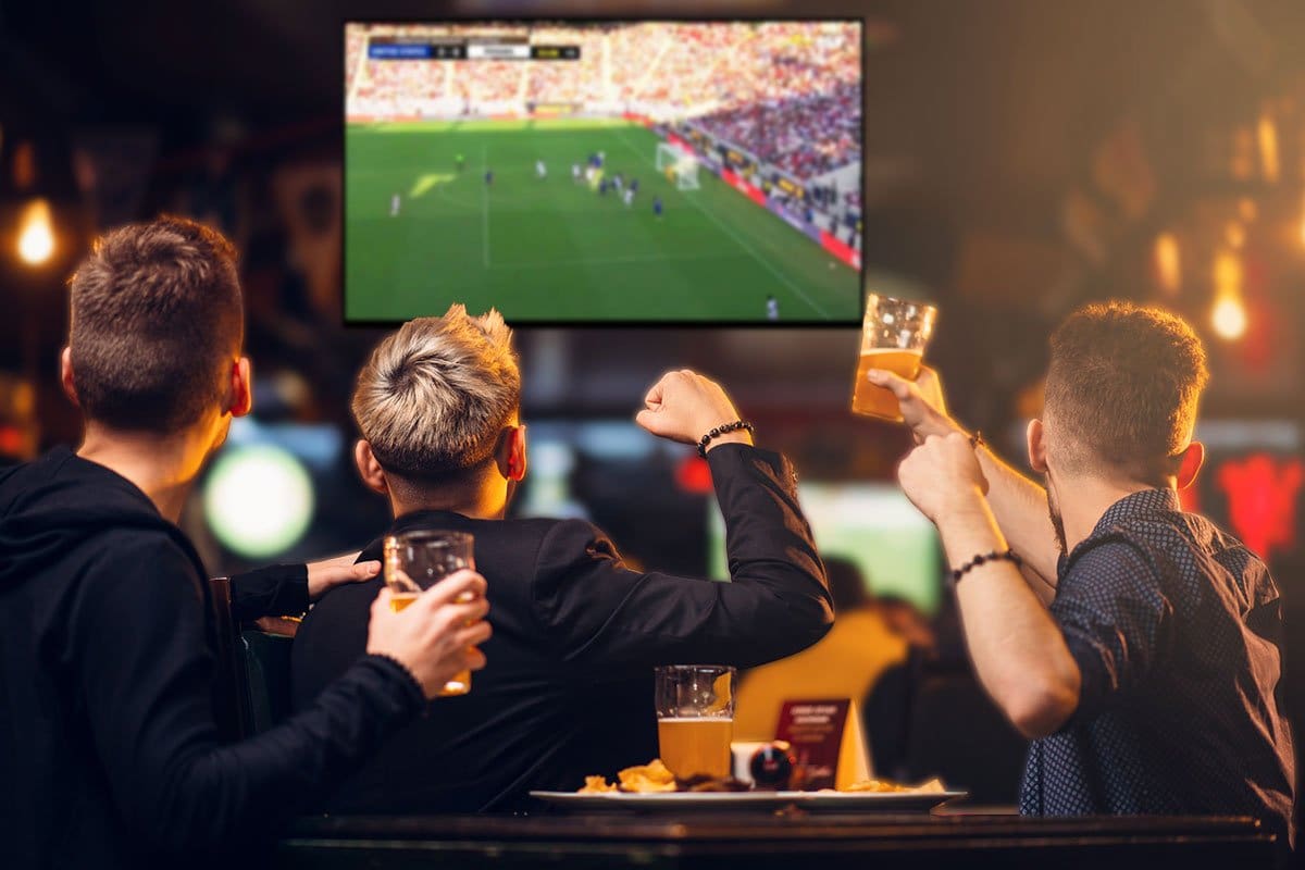 Three men watching a soccer game and having drinks in a sports bar