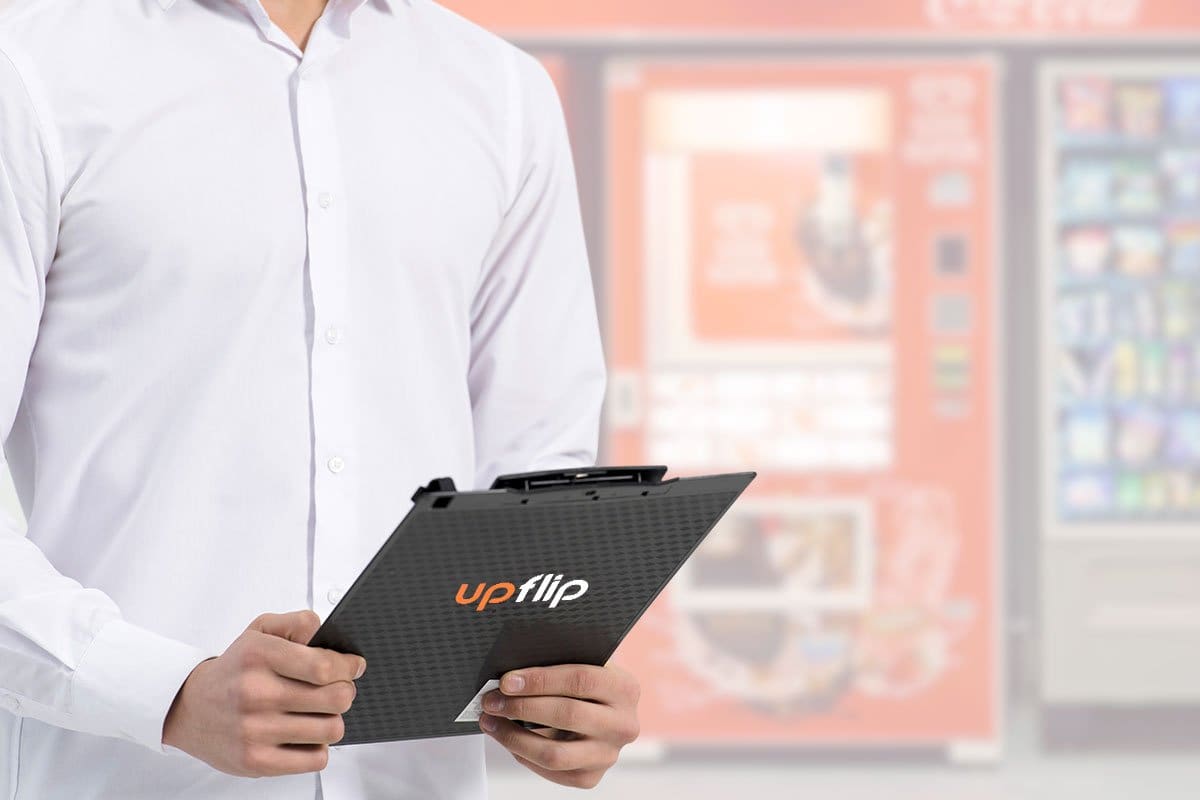 Person holding UpFlip clipboard in front of modern vending machine