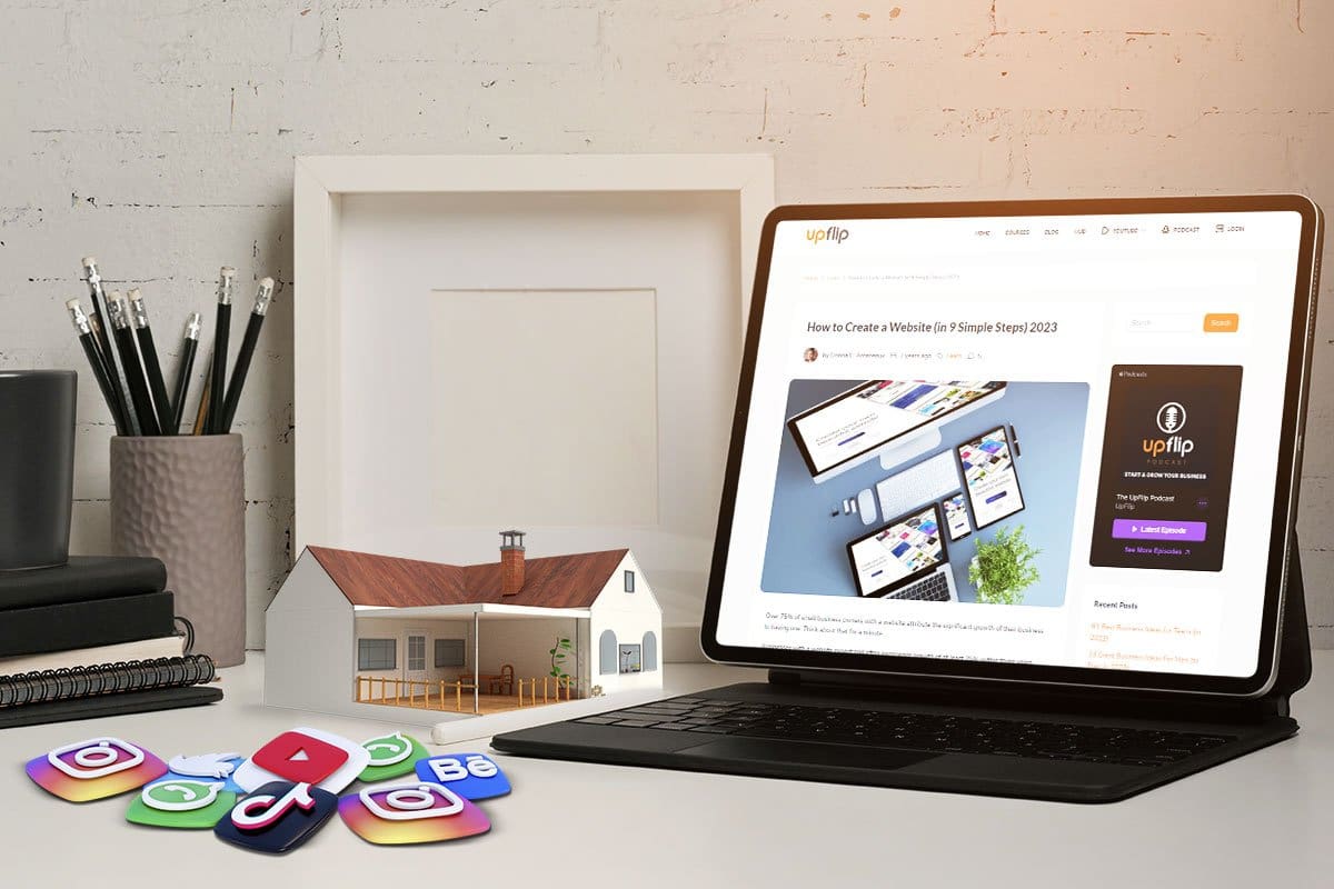 UpFlip’s "How to Create a Website" blog post on a tablet at a desk with miniature house and trinkets representing Instagram, YouTube, and other social media