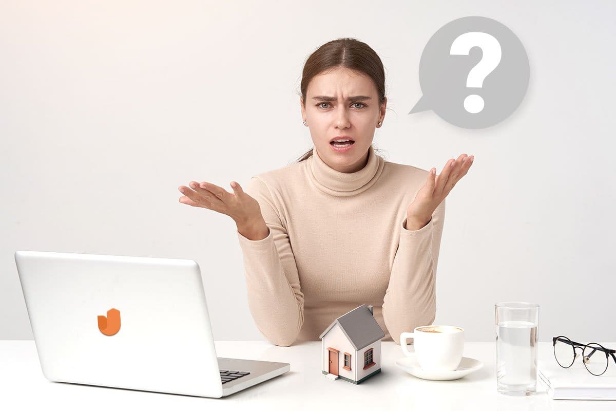 Concept of woman feeling confused about starting a home business shown with laptop, coffee, miniature house model, and question mark speech bubble