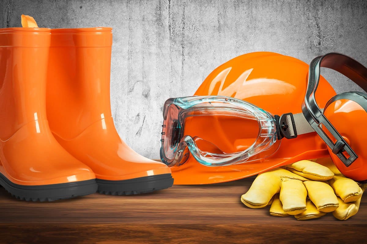 Best Pressure Washer Trailer Setup (2025) 3 Collection of correct personal protective equipment for power washing, including rubber boots, hard hat, earmuffs, gloves, and goggles