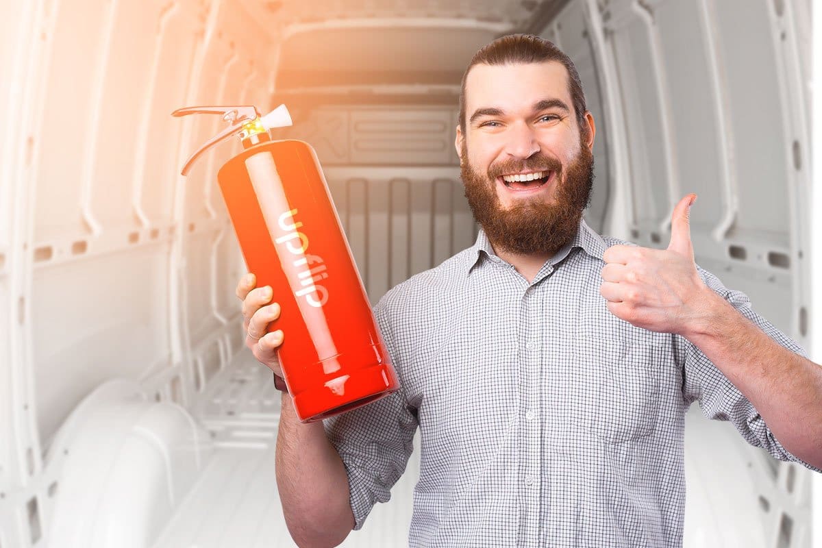 Bearded man holding an UpFlip branded fire extinguisher in front of an empty food truck