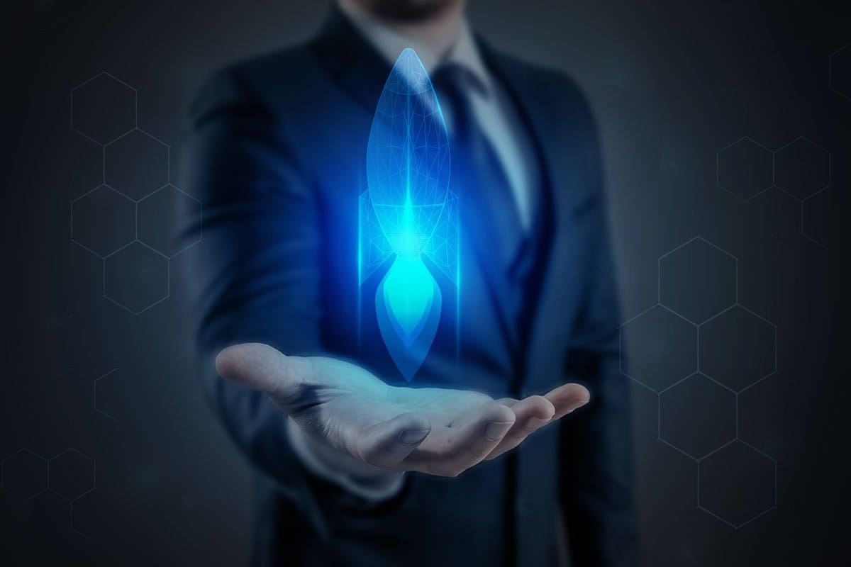 27 Best Tech Startup Ideas (2025) 1 Business tech concept showing man dressed in a suit with a blue holographic rocket hovering in the palm of his hand