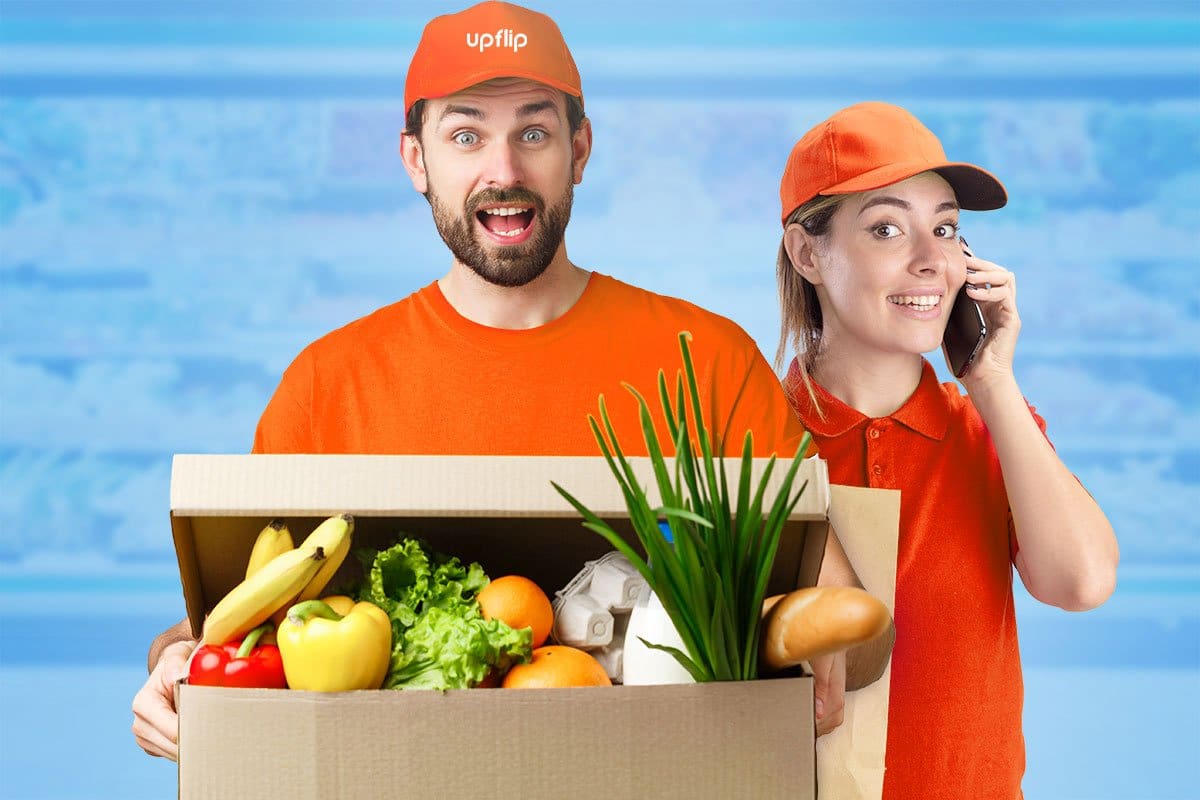 Couple curating a box of fresh produce, eggs, and baguette