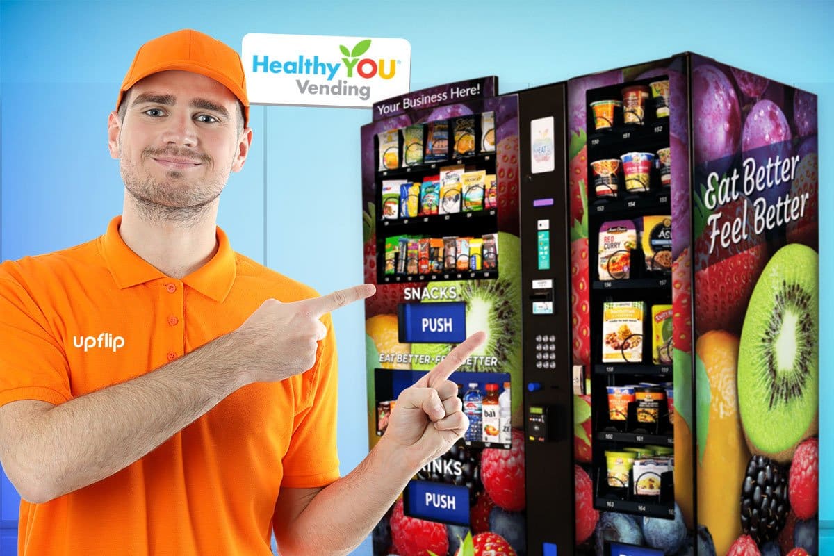 Man in orange polo and ball cap pointing to fresh healthy vending options in two HealthyYOU vending machines.
