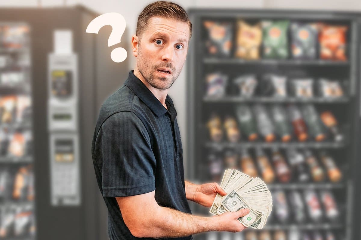 Concept of Adam Hill holding dollar bills in front of snack vending machines to show relatively small investment required to start a vending franchise 