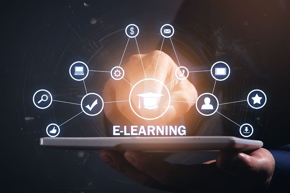 27 Best Tech Startup Ideas (2025) 2 eLearning platform concept showing a web of icons including graduation cap, thumbs up, laptop, phone, and dollar sign hovering over a tablet