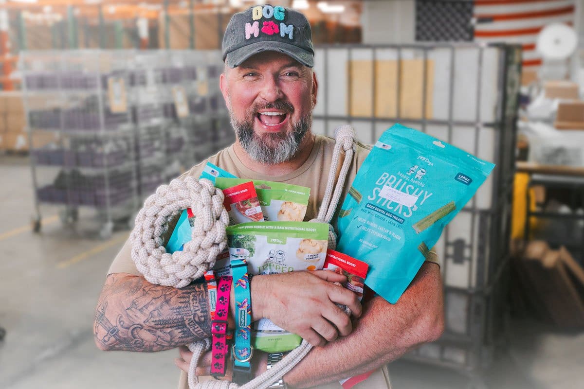 23 eCommerce Business Ideas You Can Start Today 11 Pet ecom business owner holding an armful of pet toys and treats in his warehouse