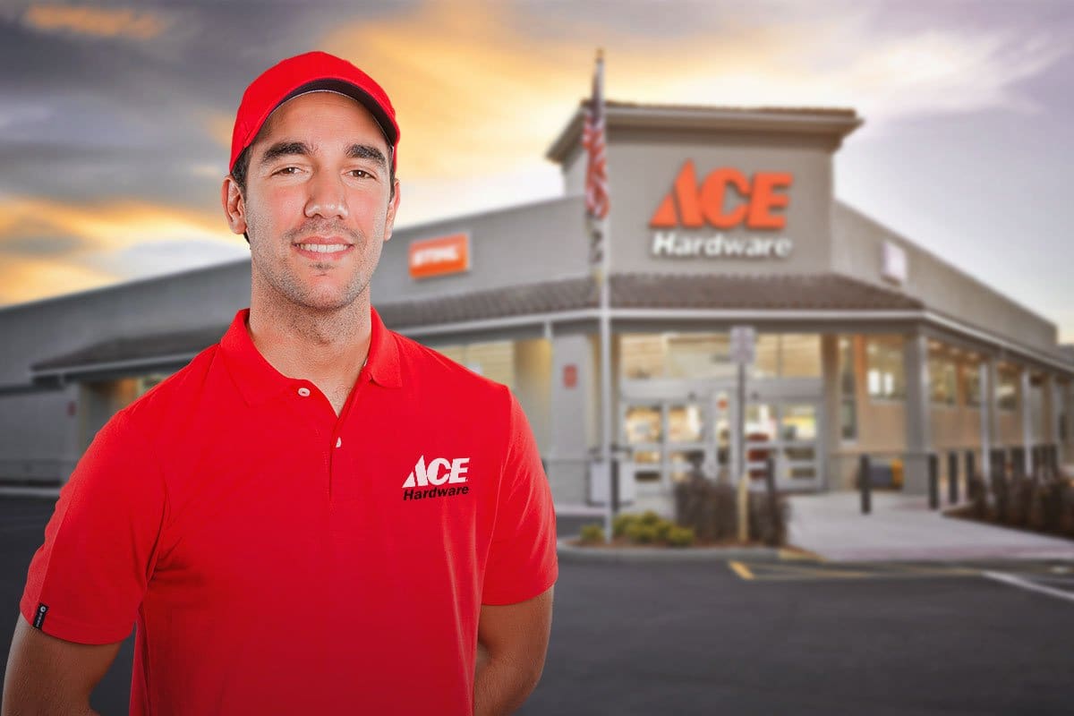 Ace hardware employee in a red ball cap and polo shirt standing in front of an Ace Hardware store