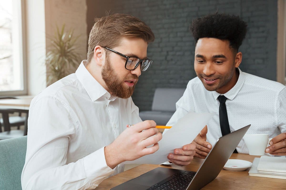 Business partners sitting down with a laptop and paperwork discussing whether they can afford to buy a new business