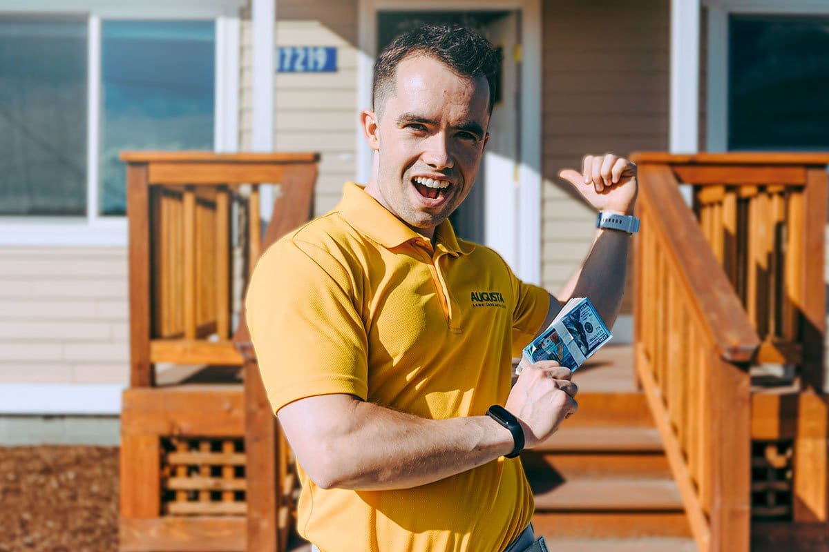 How to Become an Entrepreneur in 13 Steps 8 Mike gesturing to the porch and open door of a small home while holding a stack of hundreds in one hand
