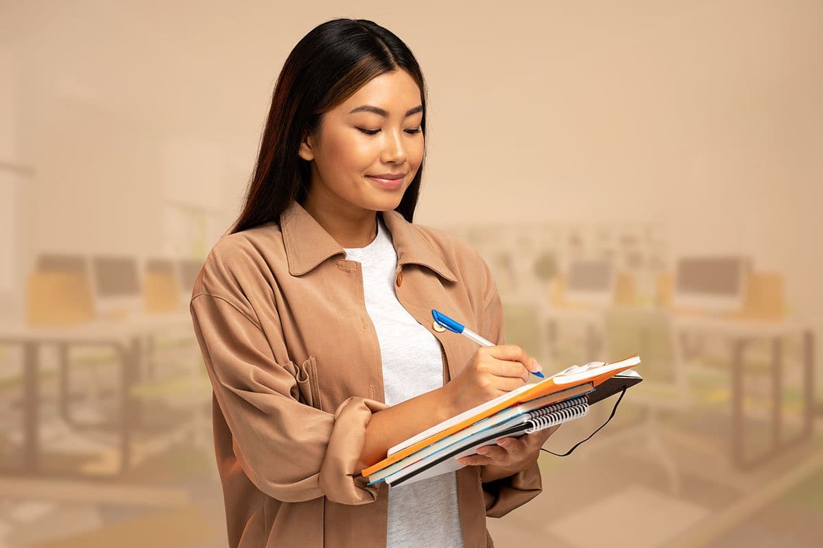 Casually dressed woman business owner jotting a note while holding folders and steno pads