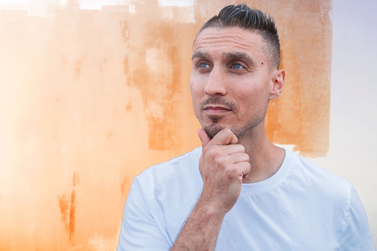 Spray-Net owner thinking in front of a partially painted exterior wall