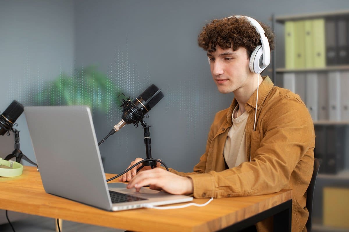 How to Grow a Podcast (2025) 8 Young man working on a laptop and wearing over-ear headphones in an organized office space