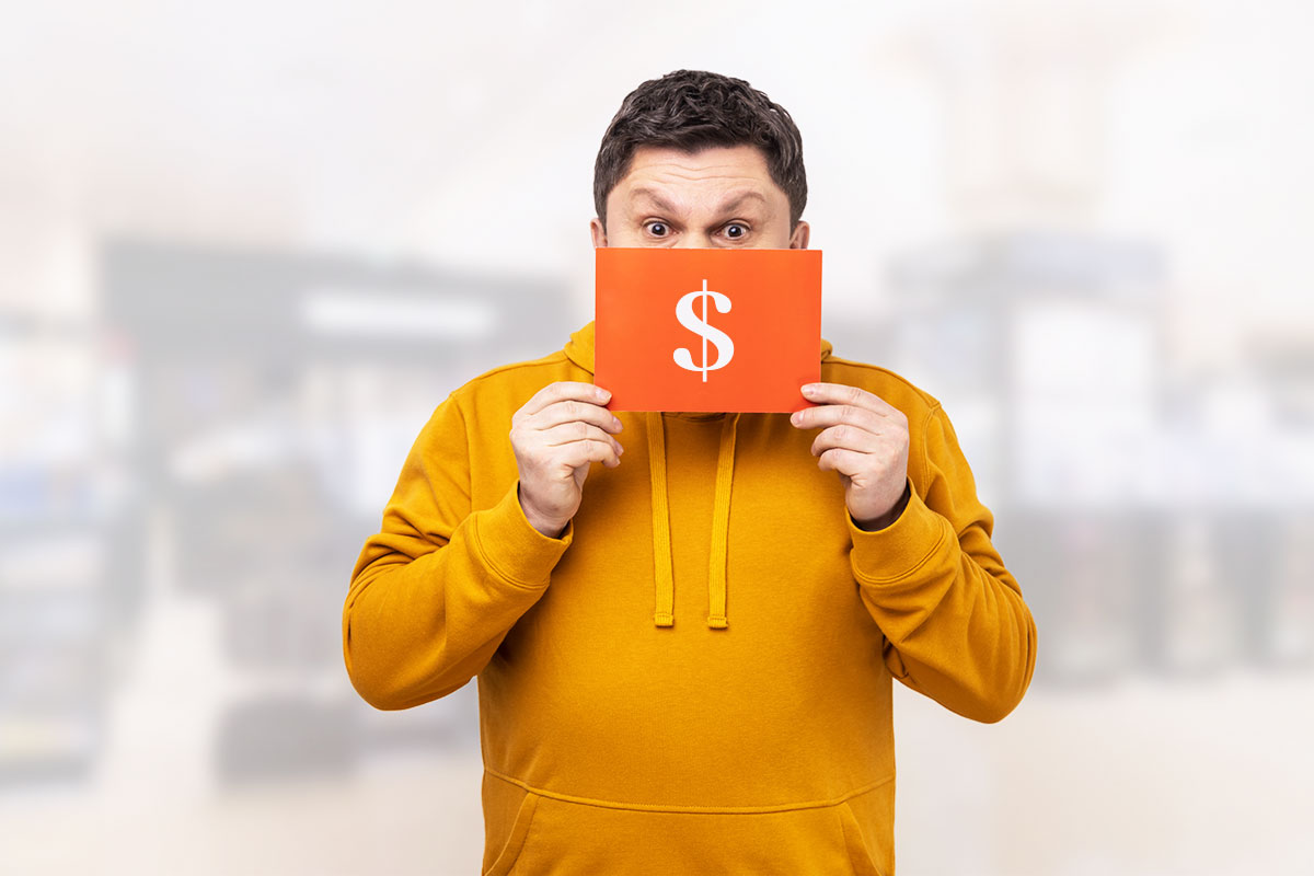 How to Start a $58K/Month Vending Machine Business 4 A man in a sweatshirt holding an orange envelope with a dollar sign