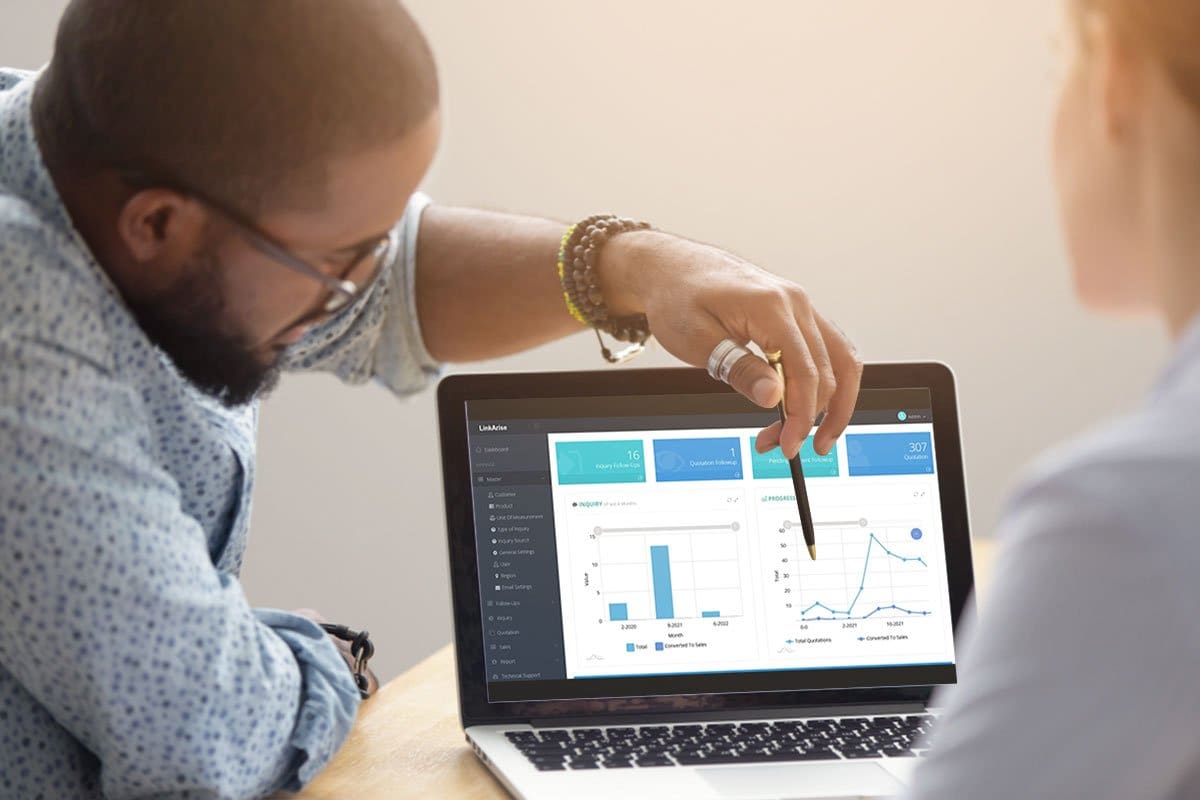 Business owner pointing to graphs on a laptop while conducting a sales opportunity management tutorial