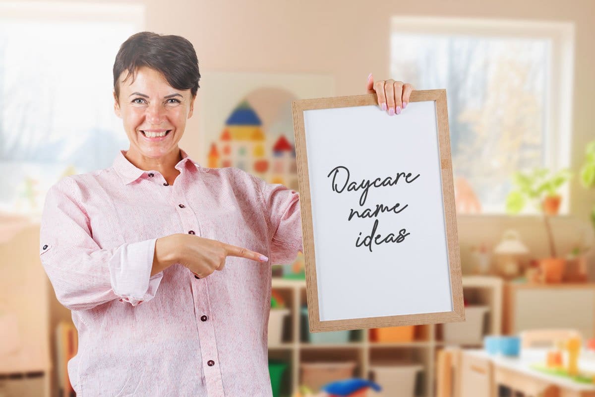698 Endearing Daycare Names (2025) 2 Middle-aged woman daycare owner pointing to a whiteboard with the words "Daycare name ideas" written on it