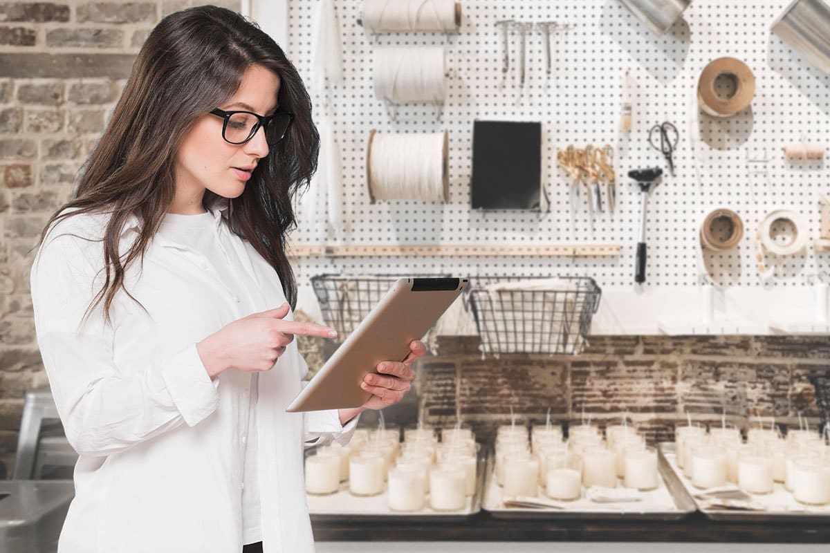 How to Start a $500K/Year Candle Business 3 Candlemaker holding a tablet in her workshop