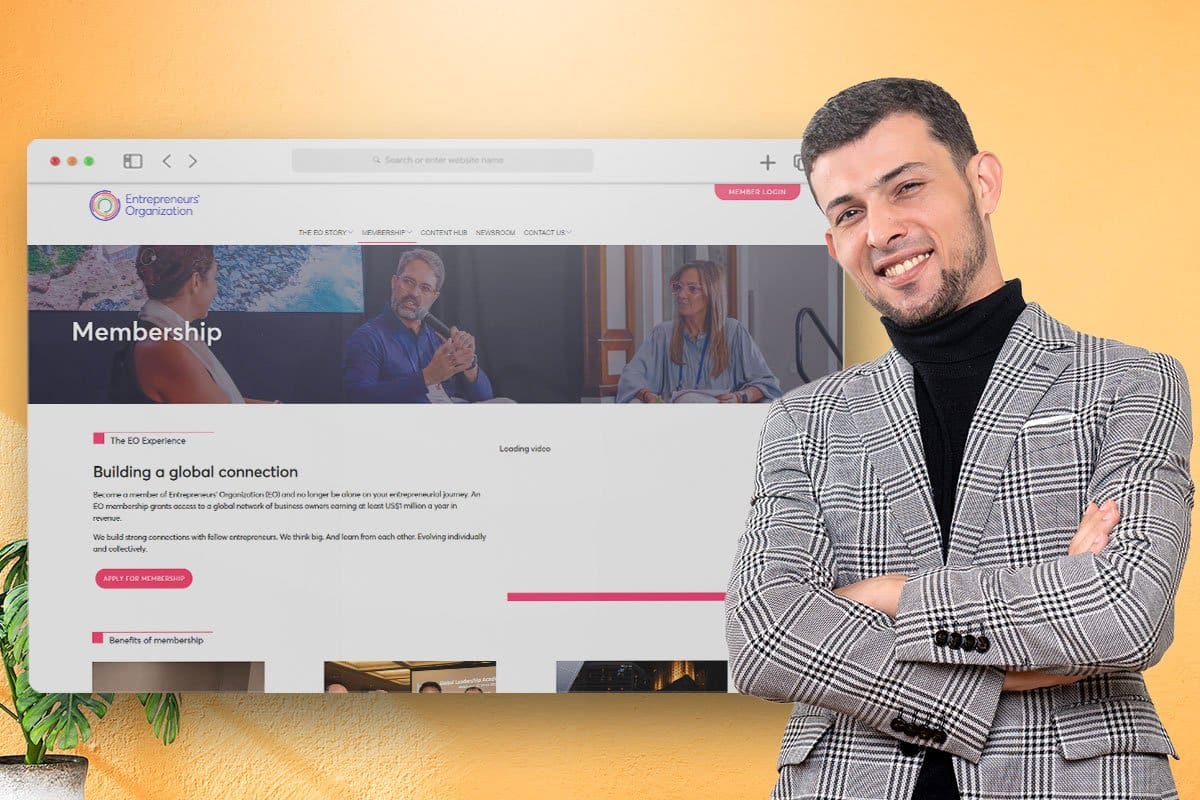 Man in a tweed sport coat standing in front of a screenshot of Entrepreneurs’ Organization’s Membership page