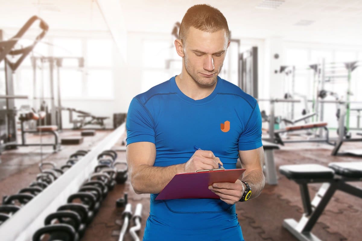 Gym owner in the free weight area writing on a clip board