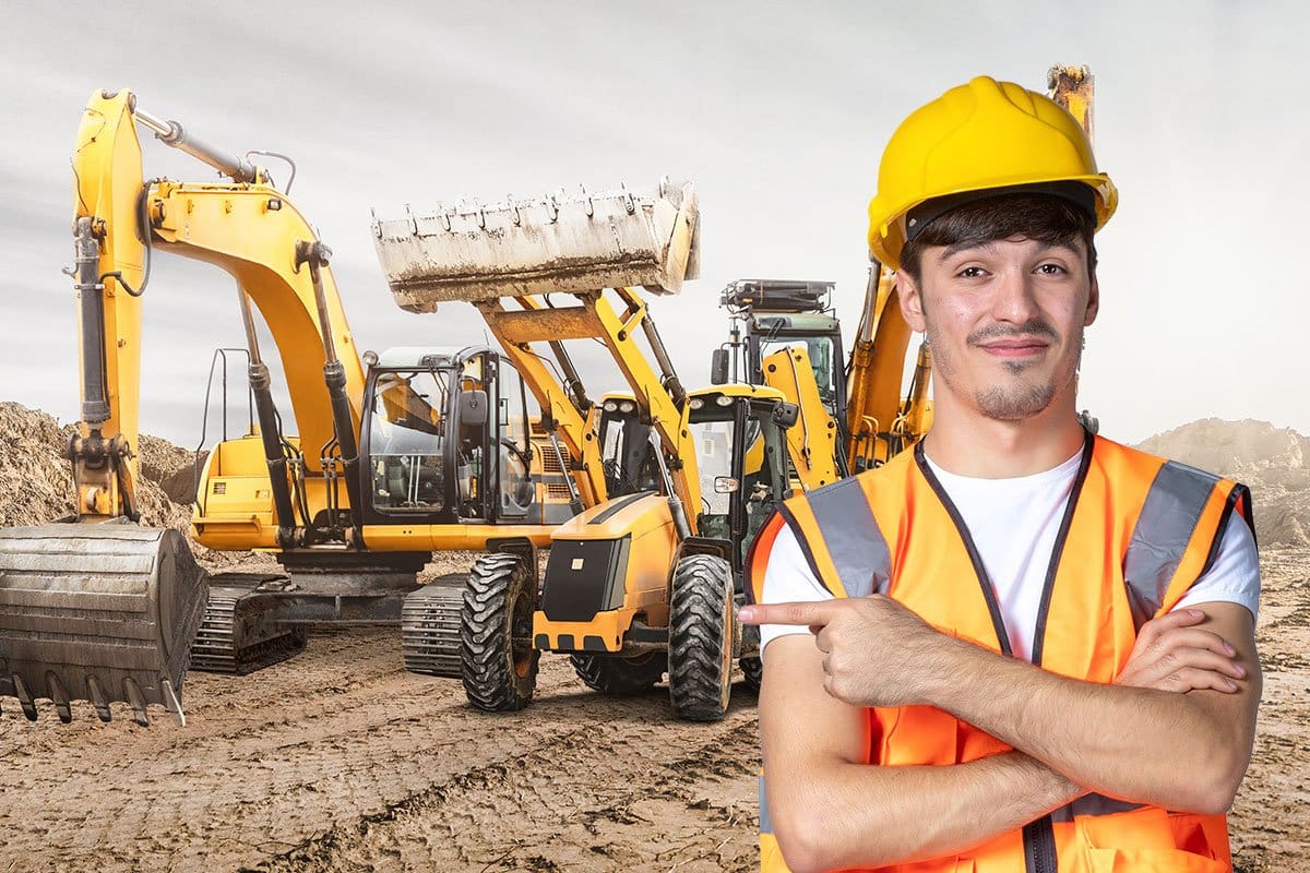 Construction worker in a hard hat and orange vest pointing to construction rigs in the background