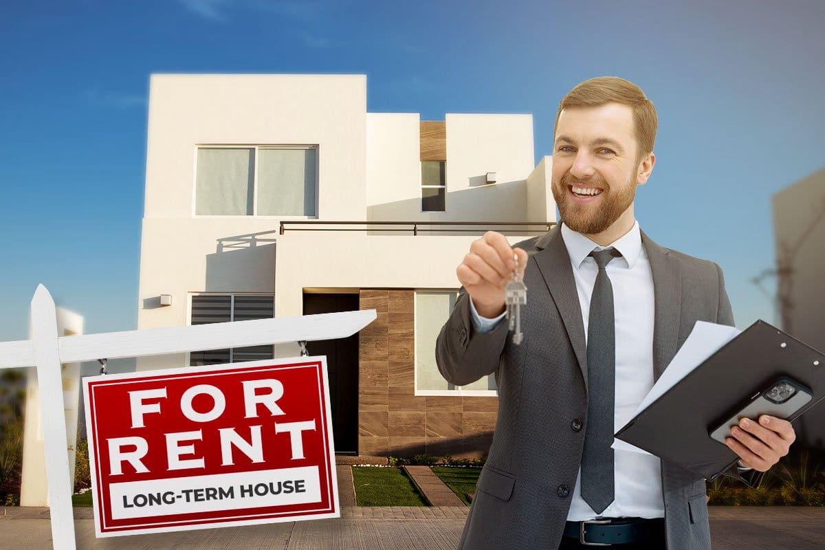 Realtor holding keys in front of a beautiful modern house with a for rent sign in the yard