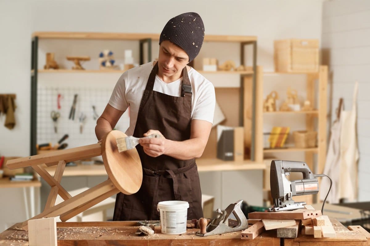 Woodworker staining a stool in his workshop