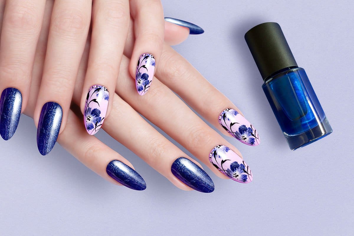 Closeup shot of a glittery blue and pink-with-blue-flowers nail art manicure