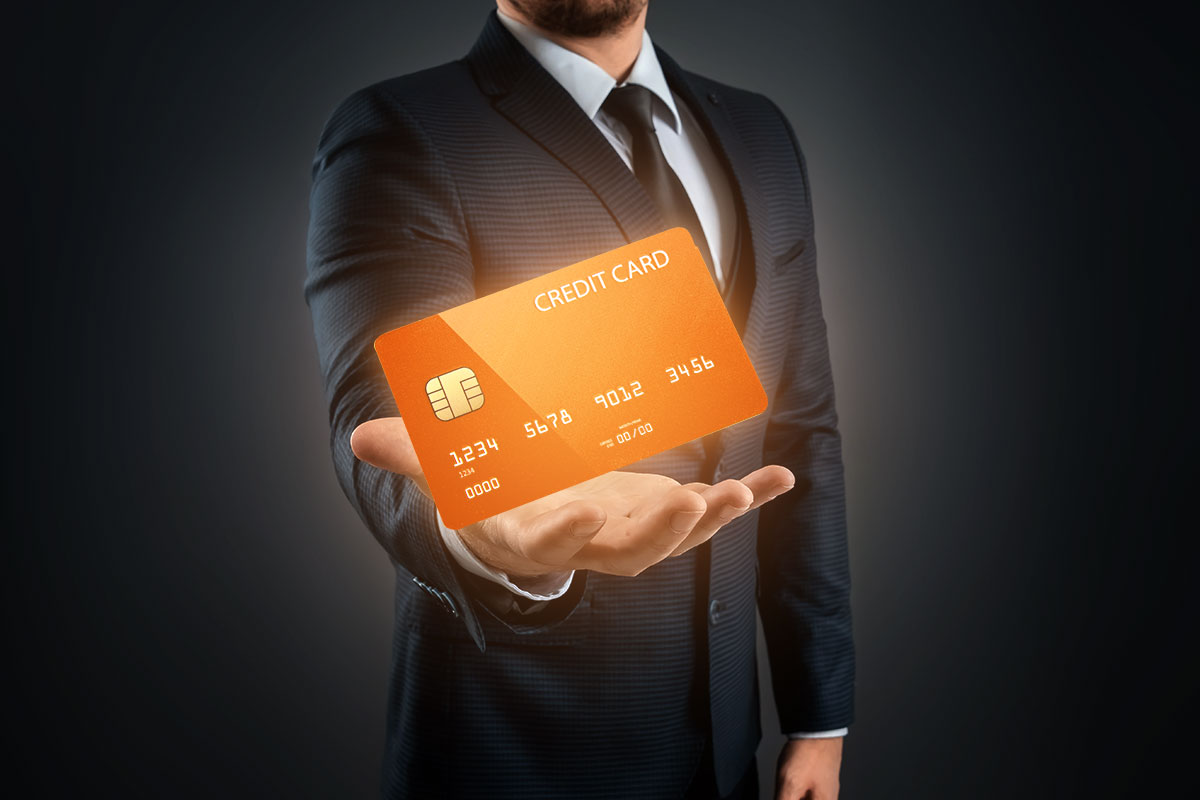 Orange business credit card hovering in the palm of a sharply dressed business man’s hand