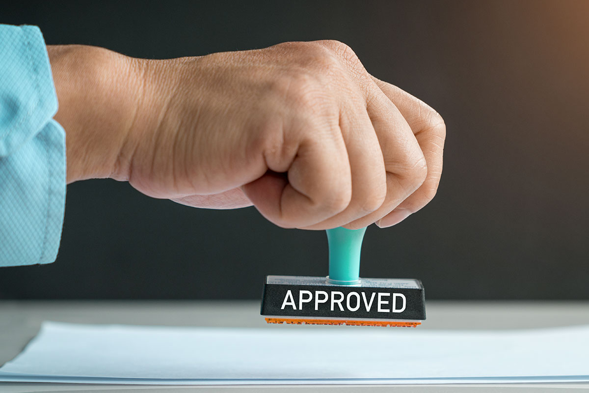 Man marking a stack of paperwork with an approved stamp