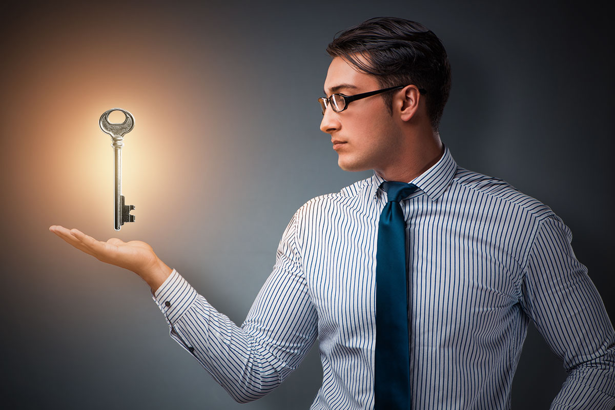 Turnkey Business: The Ultimate Guide (2025) 1 Man wearing glasses, a button down shirt, and a tie with a large silver key hovering in his hand