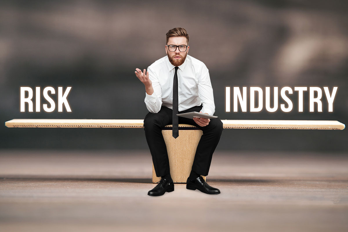 How to Build Business Credit: 6-Step Guide (2025) 2 Business man holding a tablet sitting in the middle of a seesaw with text that reads Risk on one side and Industry on the other
