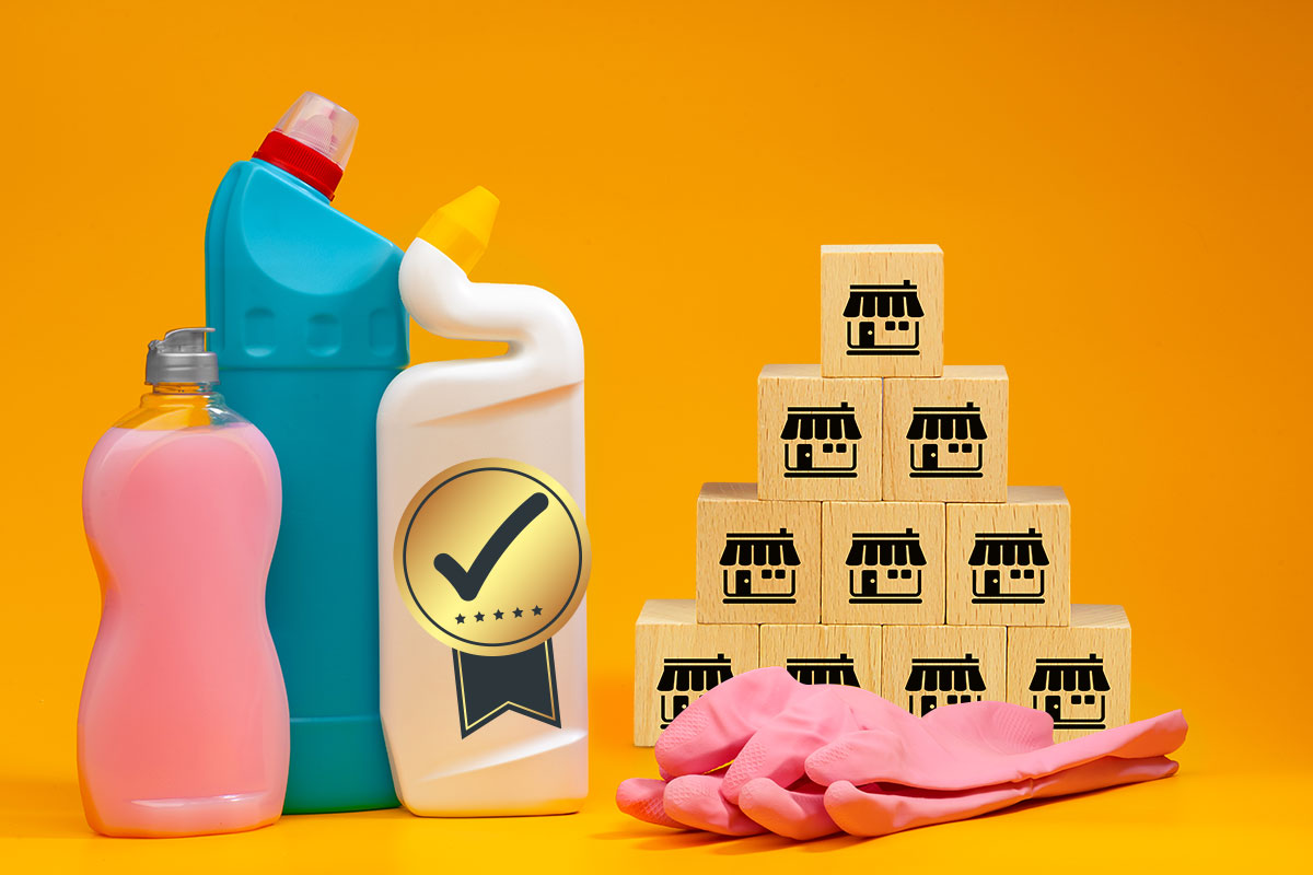 The 16 Best Cleaning Franchises to Own in 2025 7 Cleaning products and rubber gloves next to a stack of wooden blocks with tiny storefronts printed on them