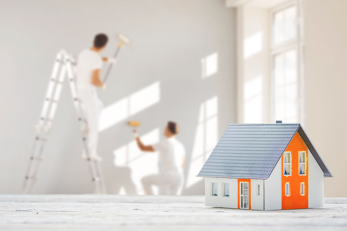 A painting crew working in a rental property with a model house in the foreground.