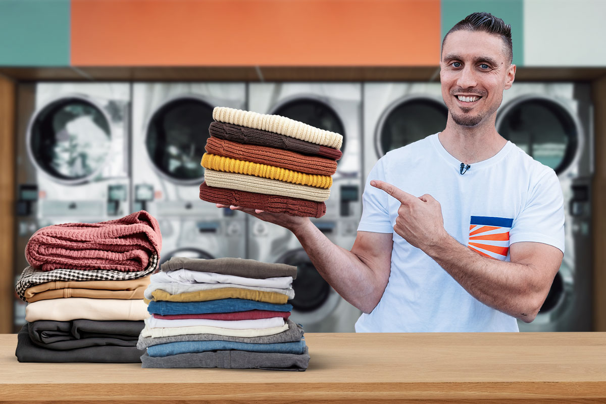 Best Laundromat Franchises of 2025 9 Laundromat owner holding a stack of folded towels inside a laundromat