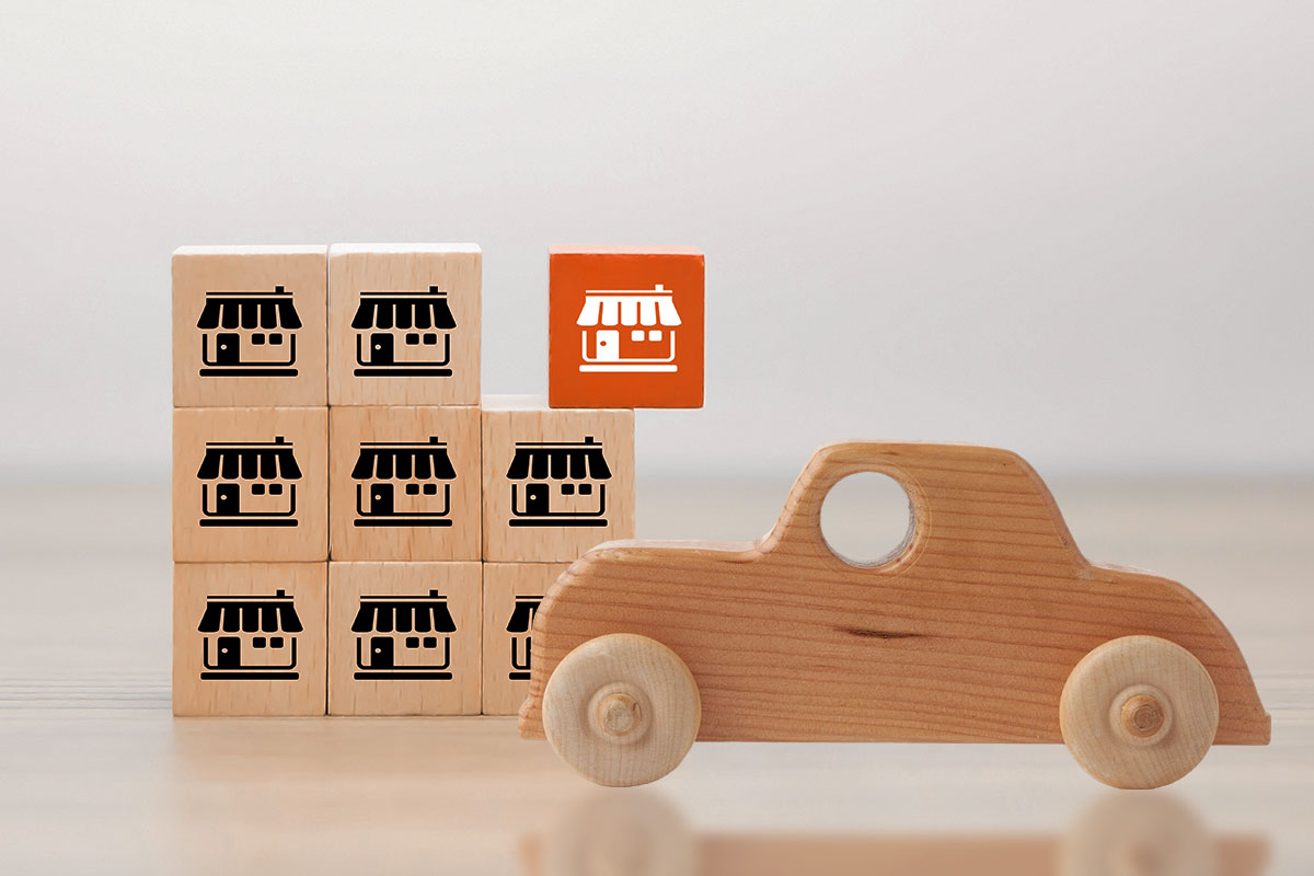 Stacked blocks stamped with a marketplace symbol next to a wooden car figurine